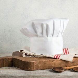 Chef's hat, antique cutting board and wooden spoons