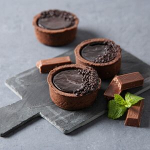 mini chocolate tarts with piece chocolate and mint on a gray background