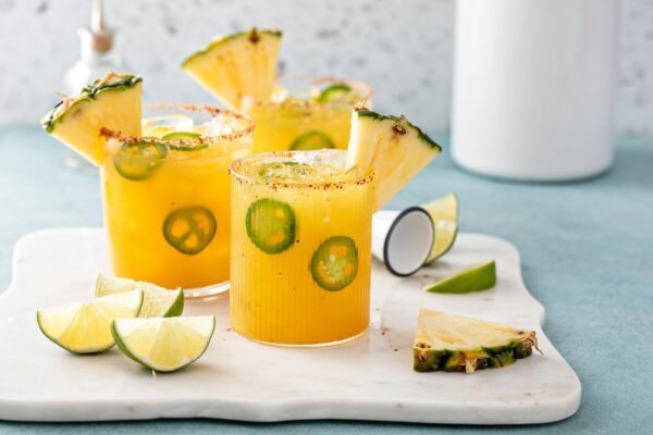 Pineapple jalapeno margarita cocktail in glasses with tajin rim