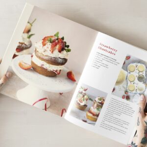 Woman reading from a recipe cookbook flat lay